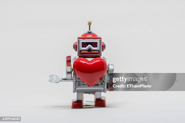 tin toy robot in love - robotic heart stock-fotos und bilder