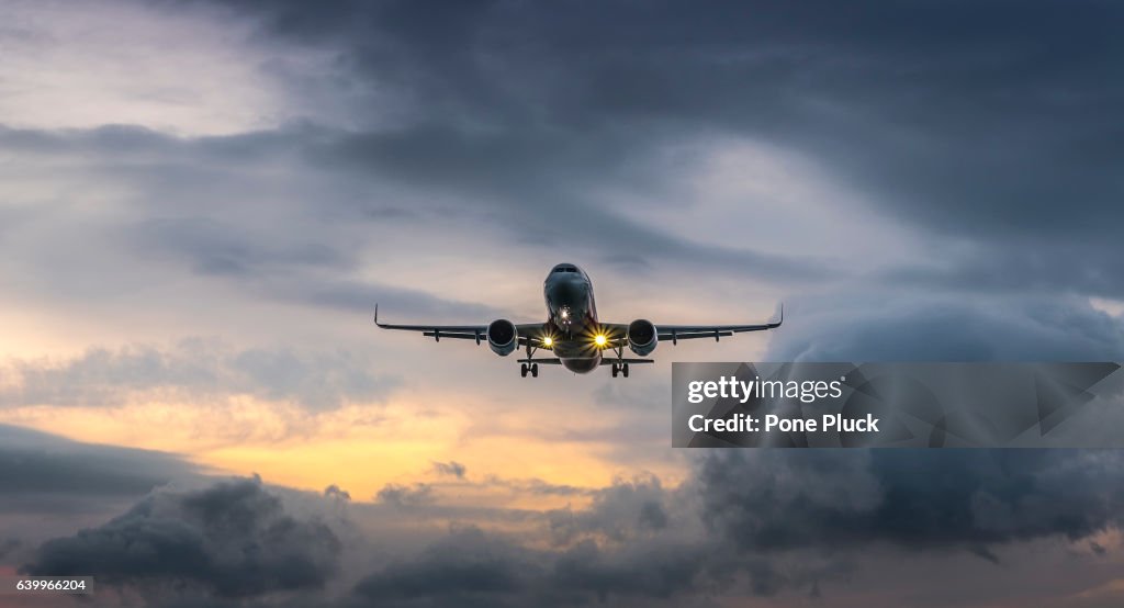 Airplane landing in dramatic sunset