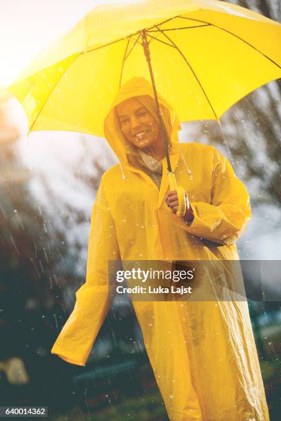 junge frau im gelben regenmantel auf dem regen - frau mit gelben regenmantel stock-fotos und bilder