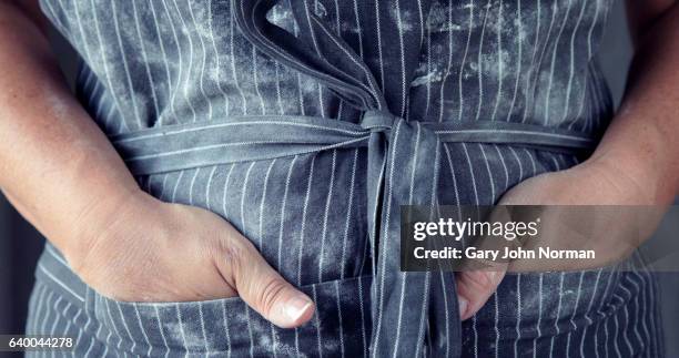 midsection female baker relaxing with hands in pocket of apron - tablier photos et images de collection