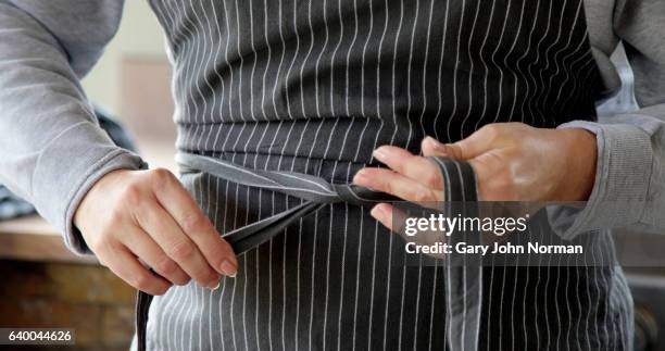 close up of woman tying apron at front of body - tie close up stock-fotos und bilder