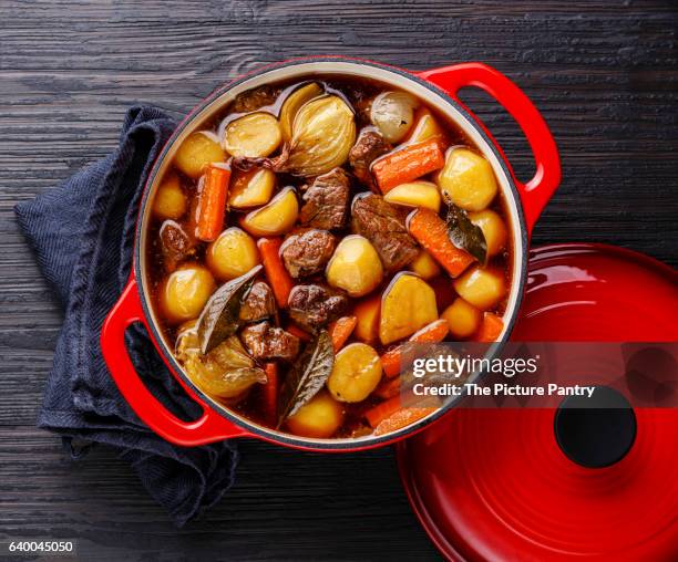 beef meat stewed with potatoes, carrots and spices in cast iron pot on burned black wooden background - stew pot photos et images de collection