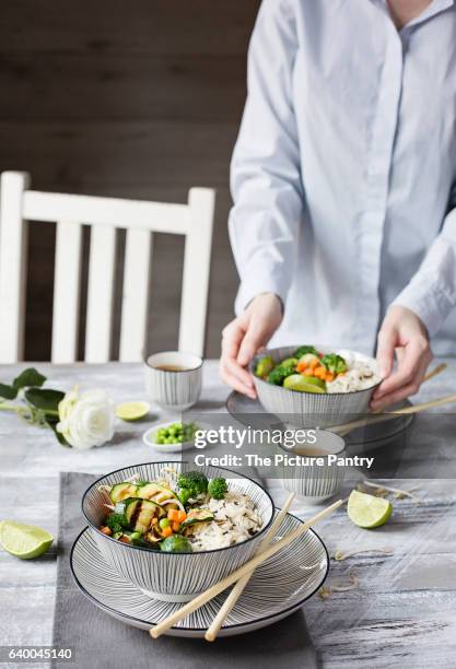 a woman serving basmati rice with vegetables on grey background - basmati rice stock-fotos und bilder
