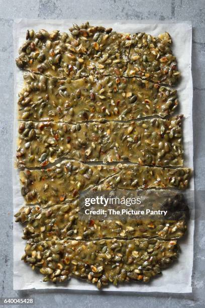 toasted pumpkin seed brittle on a parchment paper.top view - praline stock pictures, royalty-free photos & images