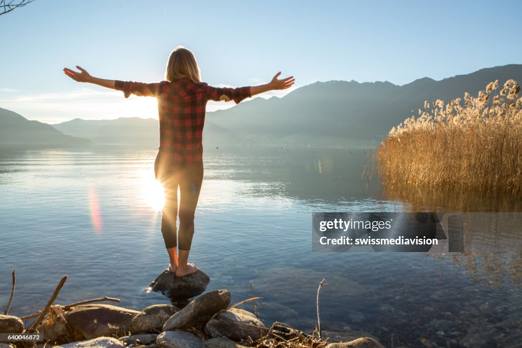 Young cheerful woman by the lake enjoying nature