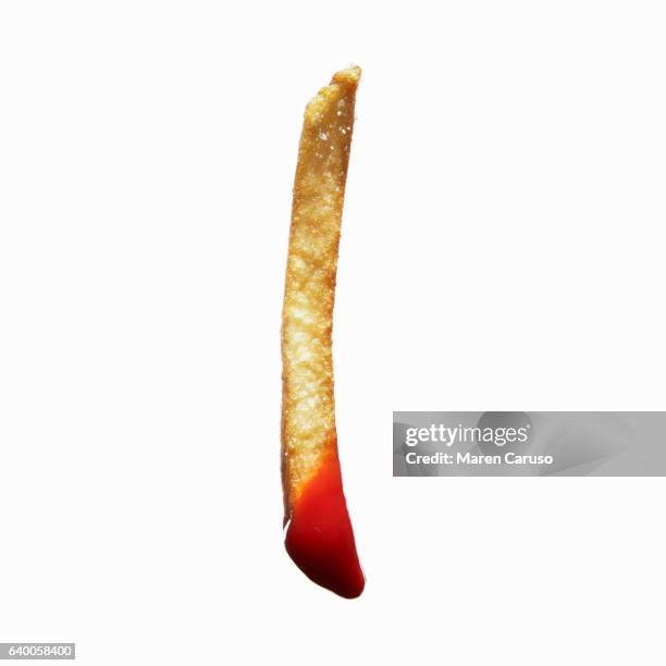 french fry dipped in ketchup - frites stockfoto's en -beelden