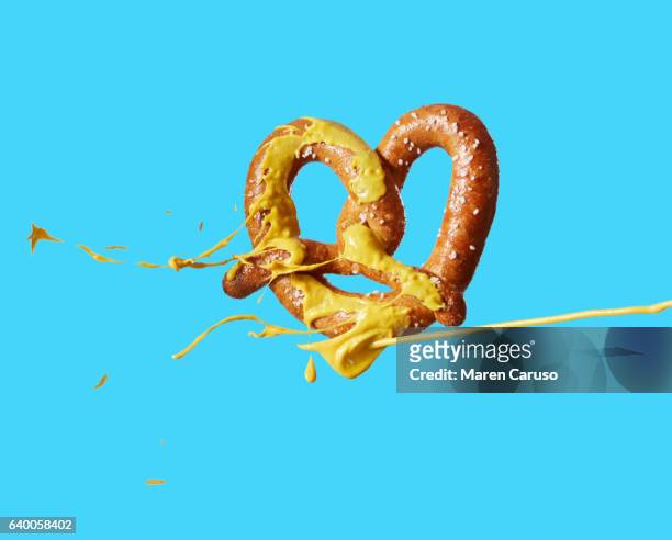 mustard squirting on pretzel - moutarde assaisonnements et vinaigrettes photos et images de collection