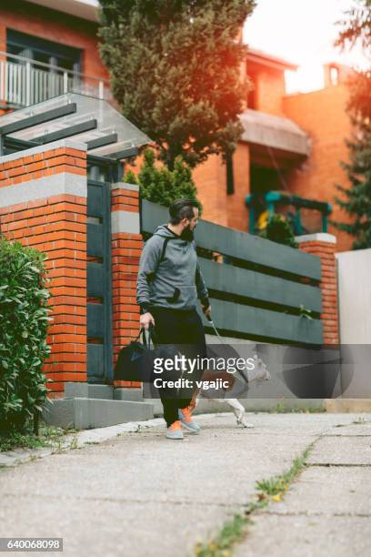 uomo fare jogging con il cane. - carrying sports bag foto e immagini stock