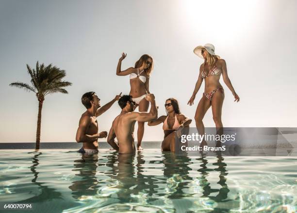 happy friends having fun at the infinity pool. - pool party stock pictures, royalty-free photos & images