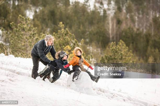 glücklicher junge macht schneemann mit ihrer familie - schneemann bauen stock-fotos und bilder