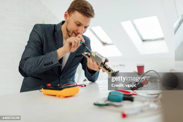 man testing circuit board in his office. - voltmeter stock pictures, royalty-free photos & images