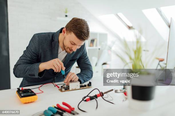 man testing circuit board in his office. - voltmeter stock pictures, royalty-free photos & images