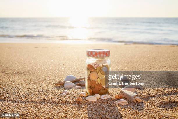 euro bank note and coins in jar at the beach during sunset - bank holiday fotografías e imágenes de stock
