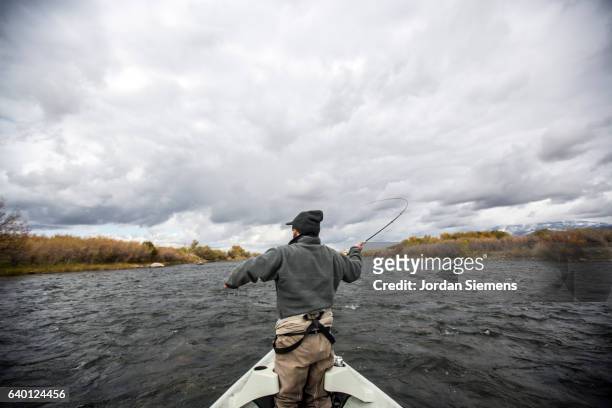 a man fly fishing on a river. - grey boot stock-fotos und bilder