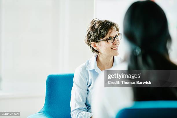 mature businesswoman listening during meeting - blue corporate imagens e fotografias de stock