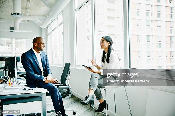 businessman and businesswoman discussing project - femme assise bureau photos et images de collection