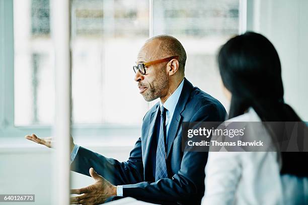 mature businessman leading meeting in office - blauw pak stockfoto's en -beelden