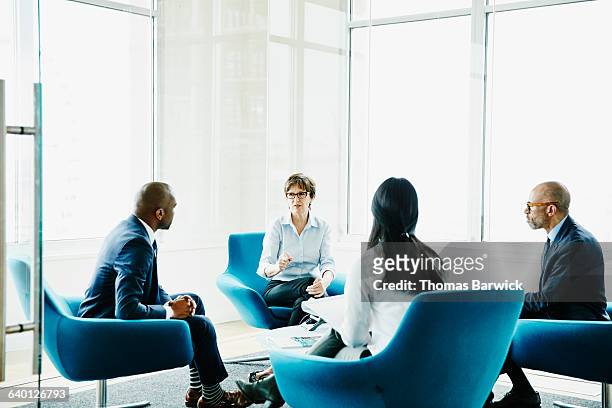 mature businesswoman leading meeting in office - blauw pak stockfoto's en -beelden