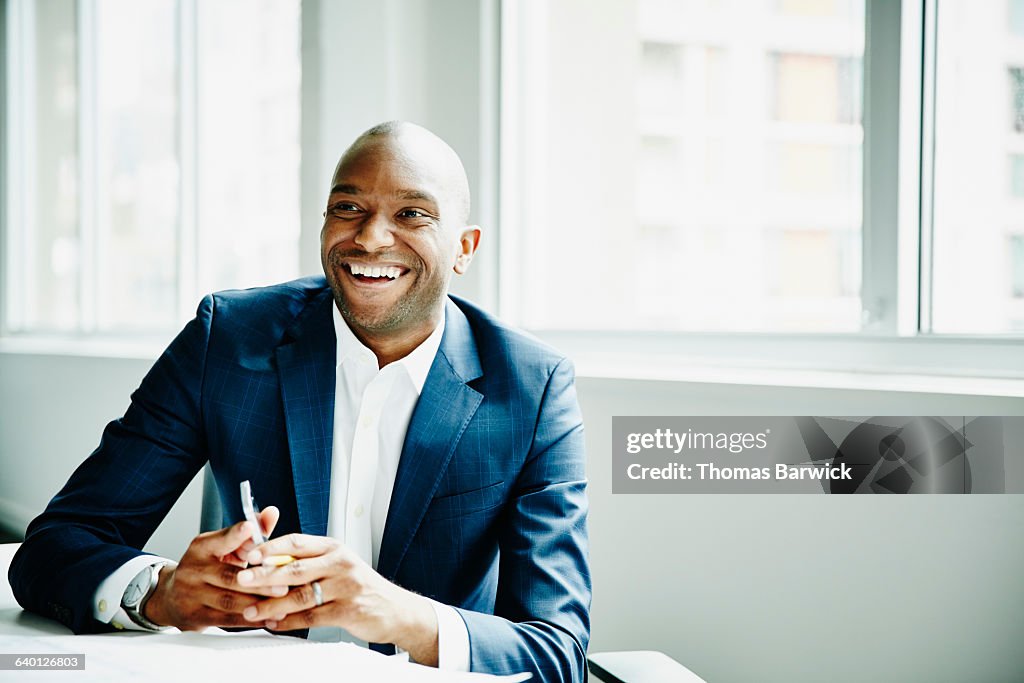 Smiling businessman in discussion at workstation