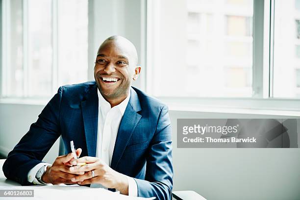 smiling businessman in discussion at workstation - traje fotografías e imágenes de stock