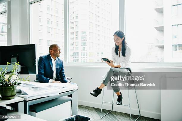 businesswoman discussing project with coworker - happy asian woman bright office stock-fotos und bilder