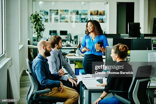 businesswoman leading meeting with colleagues - condurre foto e immagini stock