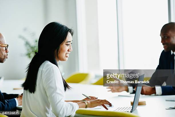 businesswoman working on laptop during meeting - happy asian woman bright office stock-fotos und bilder