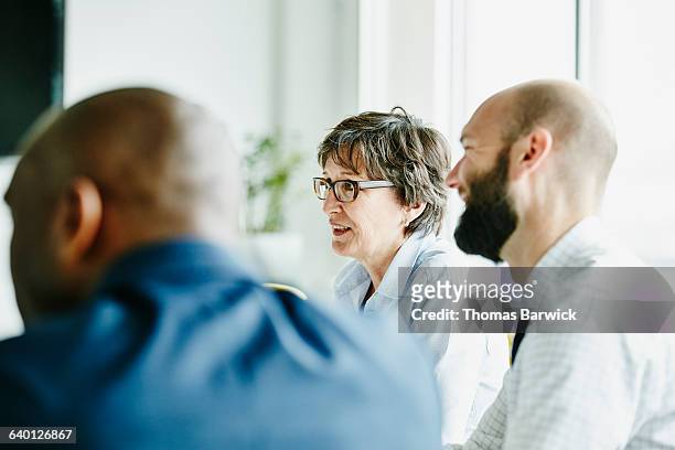 mature businesswoman leading meeting in office - differential focus stock pictures, royalty-free photos & images