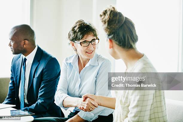 smiling businesswoman shaking hands with colleague - digital trust stock pictures, royalty-free photos & images