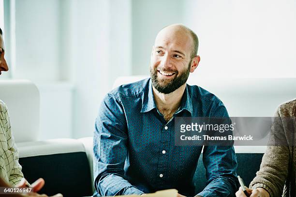 smiling businessman in discussion with colleagues - informeel zakelijk stockfoto's en -beelden
