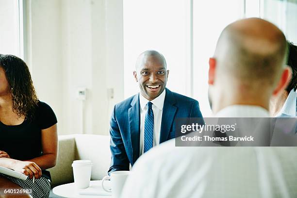 smiling businessman in discussion with colleagues - vestimenta de negocios formal fotografías e imágenes de stock