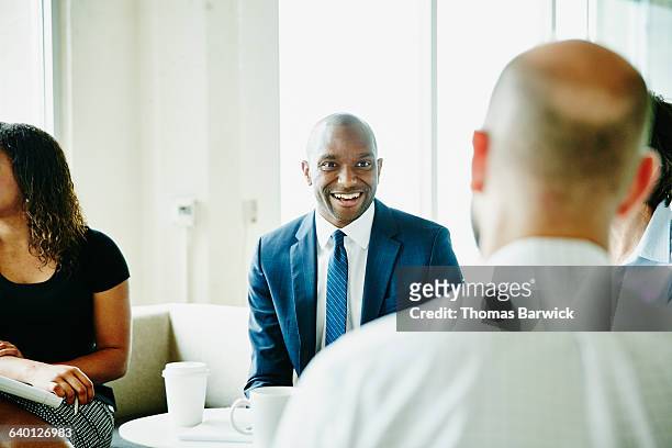 smiling businessman in discussion with colleagues - navy blue interior stock pictures, royalty-free photos & images