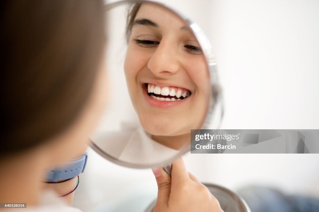 Teenage girl looking at her teeth in the mirror