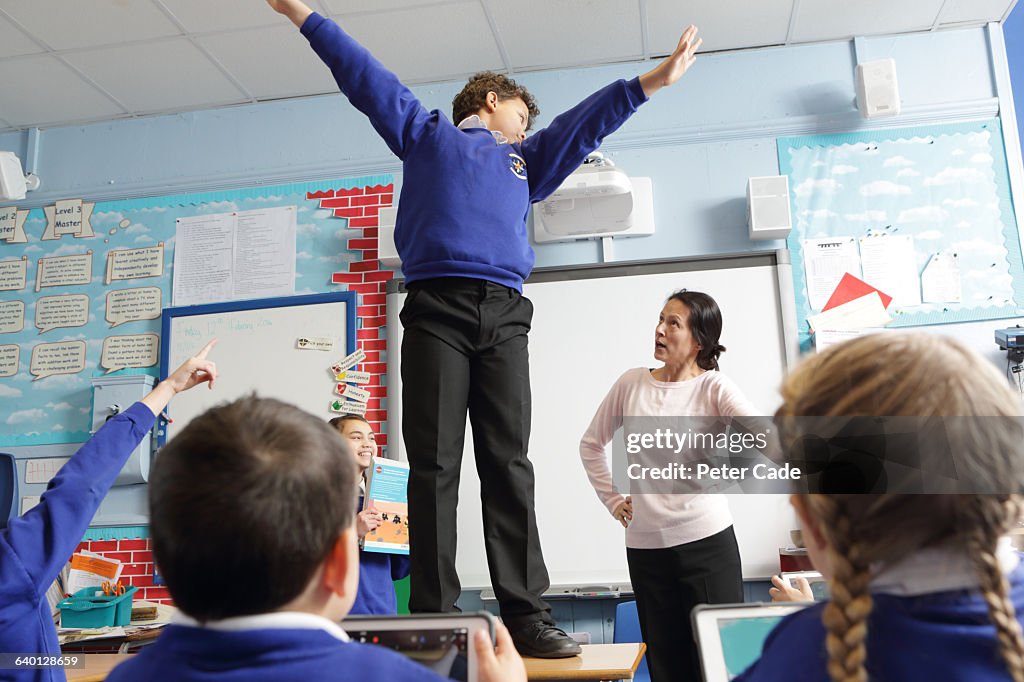 Boy in trouble for standing on table in class