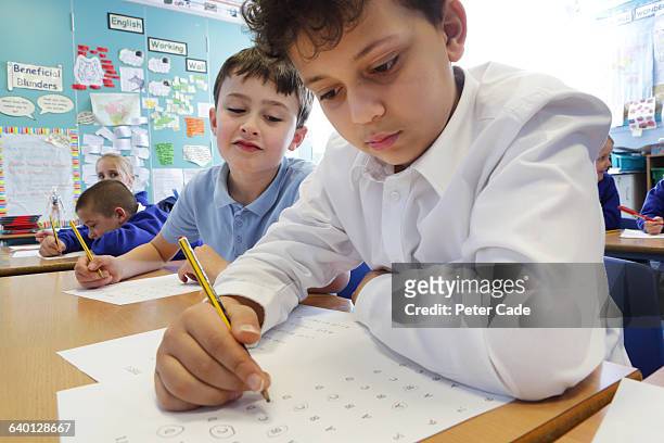 child cheating on test in classroom - copy writing stock-fotos und bilder