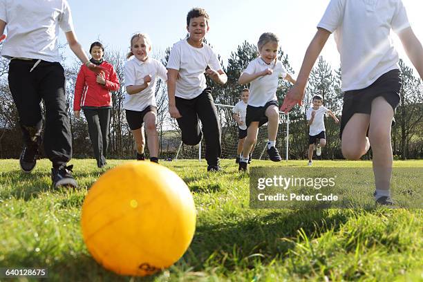 school children running for ball in field - chasing kid stock pictures, royalty-free photos & images