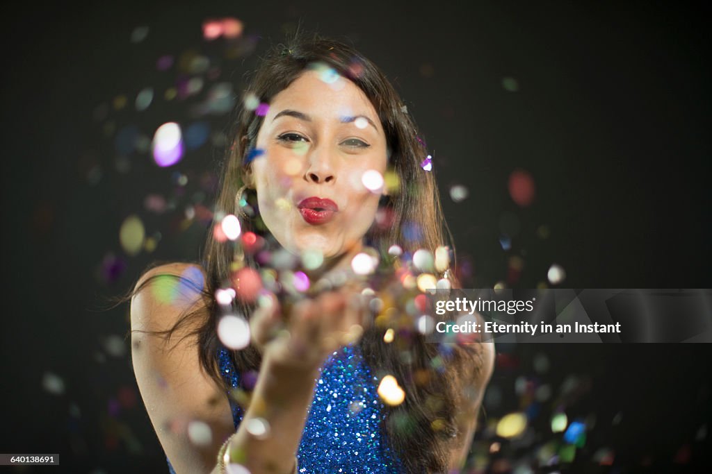 Beautiful woman blowing confetti at a party