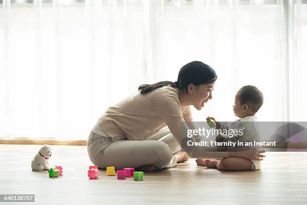mother playing with her baby at home - mum sitting down with baby stockfoto's en -beelden