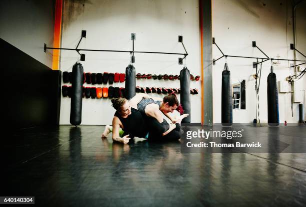 two women grappling while working out together in fighting gym - mixed martial arts fotografías e imágenes de stock