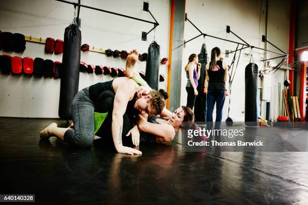 two female fighters grappling during workout in fighting gym - ring fight photos et images de collection