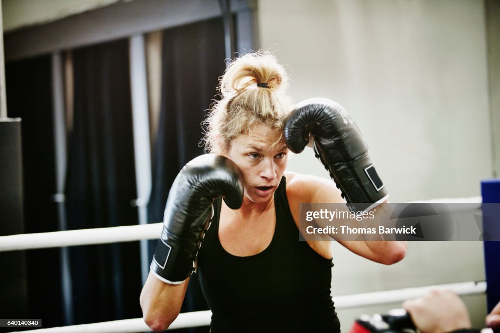 Female kickboxer working out in ring in gym