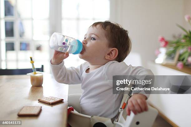 a boy taking a snack at home - baby bottle stockfoto's en -beelden