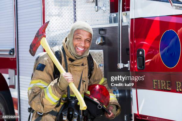 african american fire fighter carrying axe - fireman axe stock pictures, royalty-free photos & images