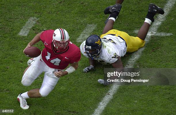 Shaun Hill quarterback of the Maryland Terrapins eludes a tackle by David Upchurch of the West Virginia University Mountaineers at Byrd Stadium on...