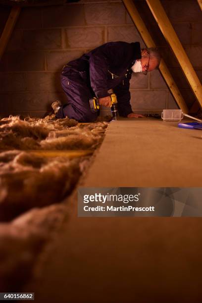 joiner laying attic floorboards - house insulation not posing stockfoto's en -beelden