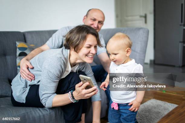 eltern zeigen ihrem kind bilder auf einem smartphone - alexandra iakovleva stock-fotos und bilder