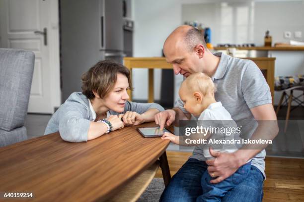 familie mit einem kind, das auf einem tablet spielt - alexandra iakovleva stock-fotos und bilder