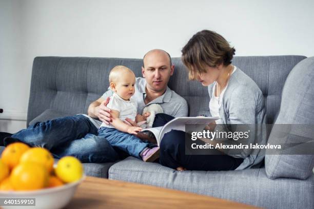 eltern lesen zusammen mit einem kind ein buch - alexandra iakovleva stock-fotos und bilder