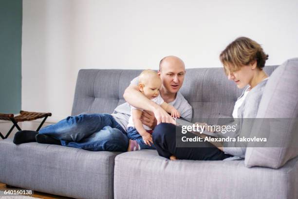 parents reading a book together with a child - alexandra mora bildbanksfoton och bilder