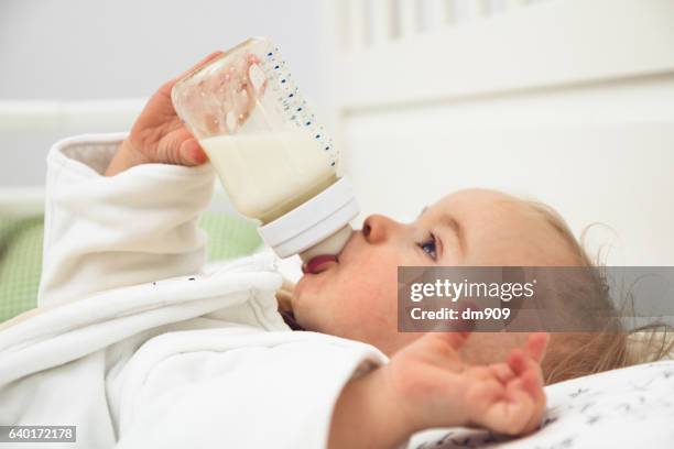 a baby is drinking milk - baby bottle ストックフォトと画像